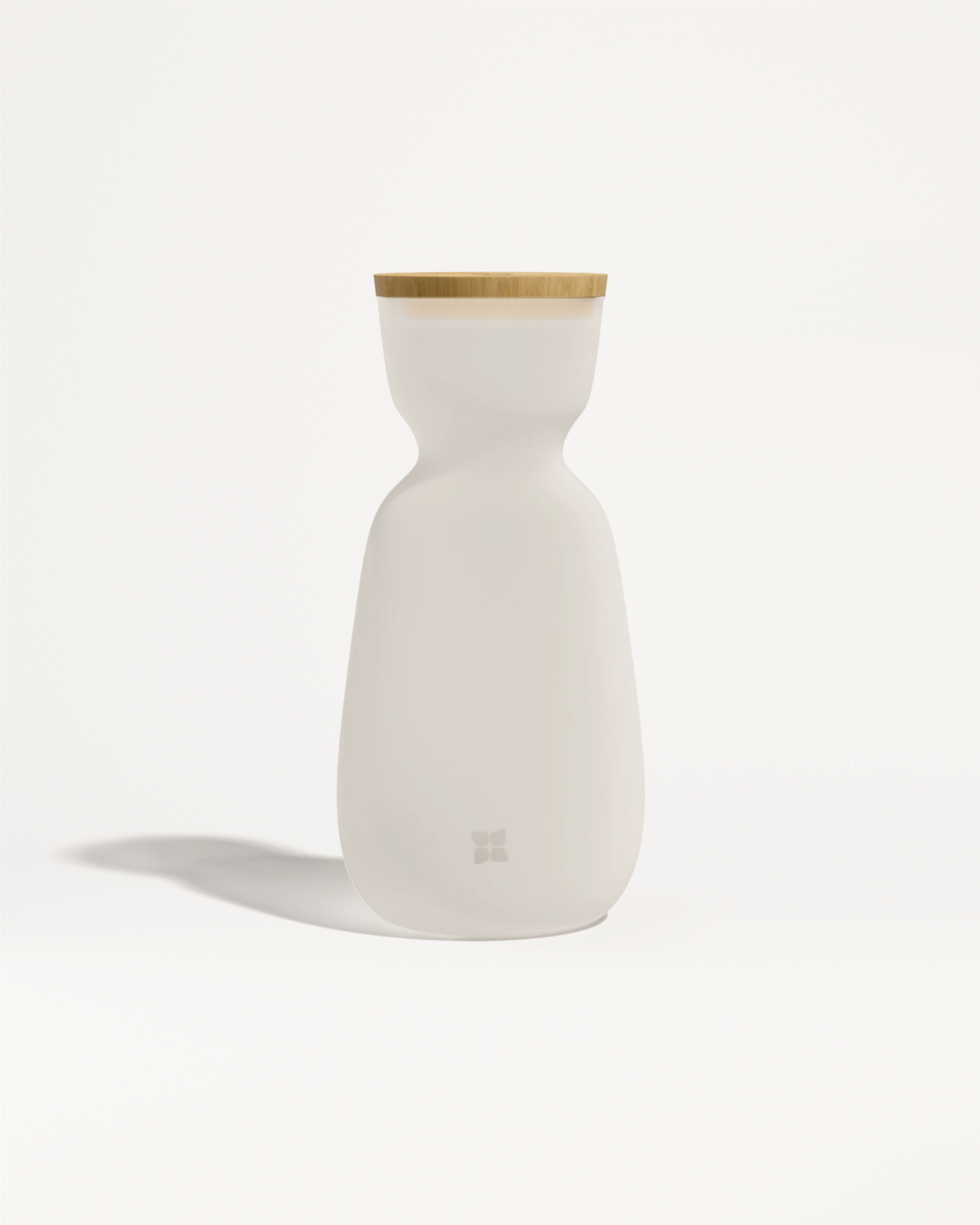 Botella blanca de cerámica con tapa de madera clara y un cuerpo suave y curvado.