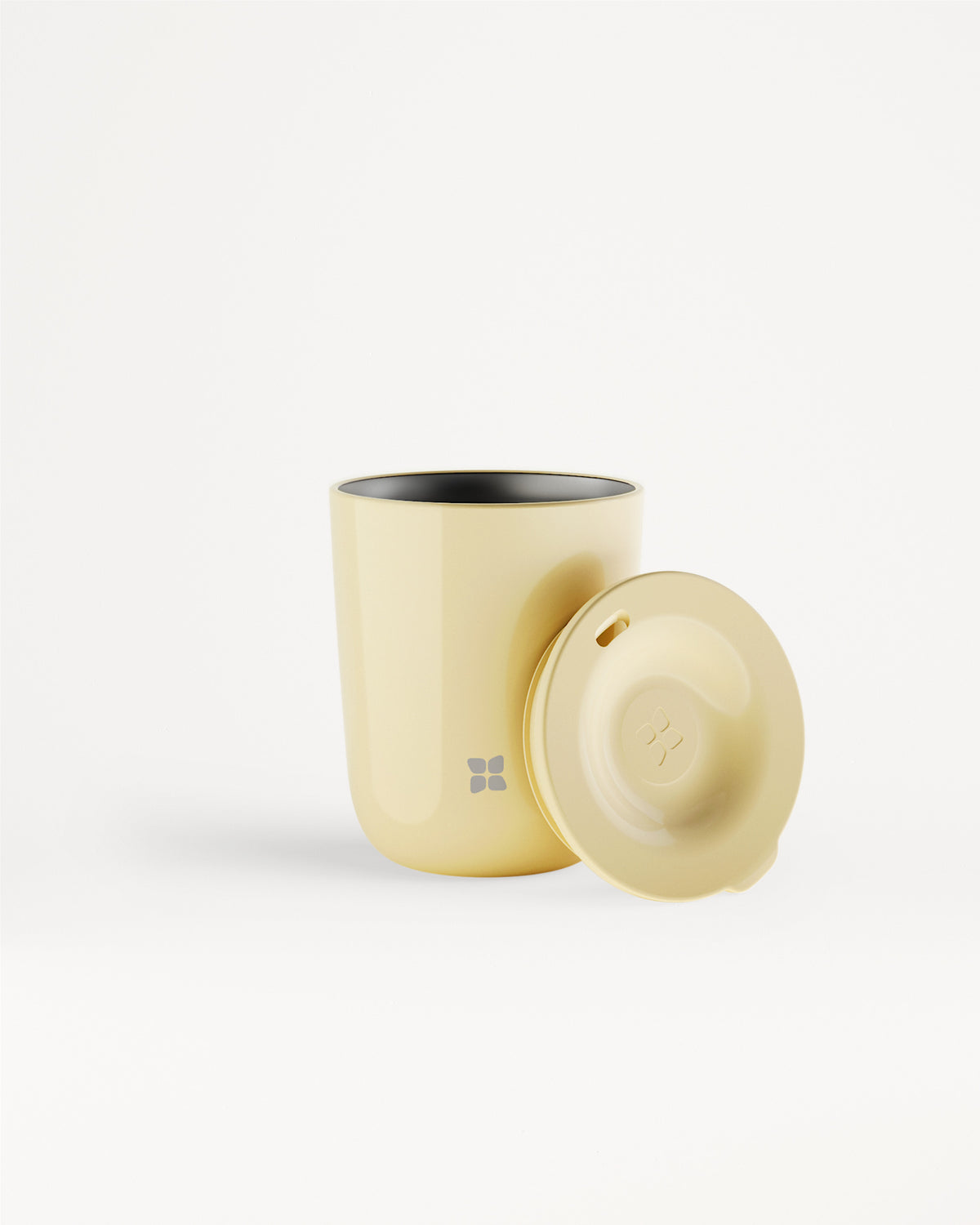 Vaso térmico beige con tapa a juego colocado junto a él.