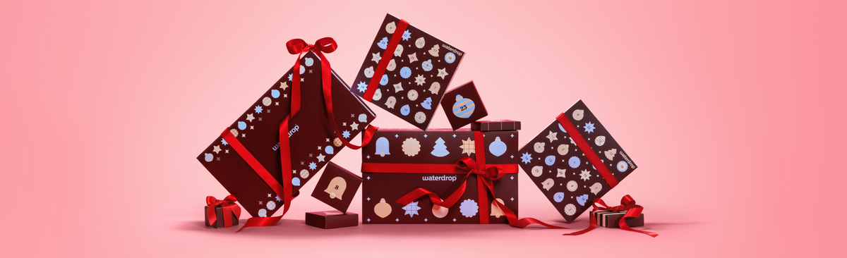 Cajas de regalo dispuestas en un arreglo festivo sobre un fondo rosa degradado.