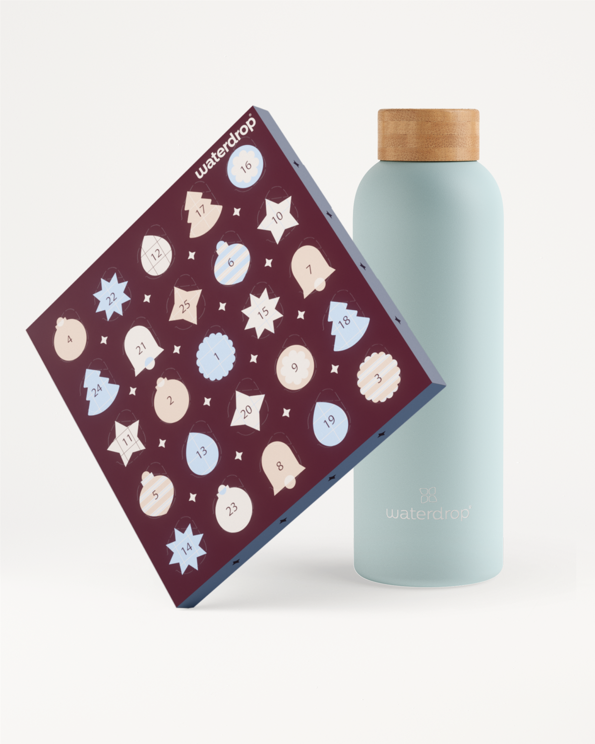 Botella azul claro reutilizable con tapa de madera junto a un calendario de adviento morado decorado con copos de nieve blancos y azules.