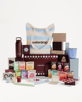 Conjunto de regalo con productos en cajas y envases variados dispuestos alrededor de una bolsa rayada.