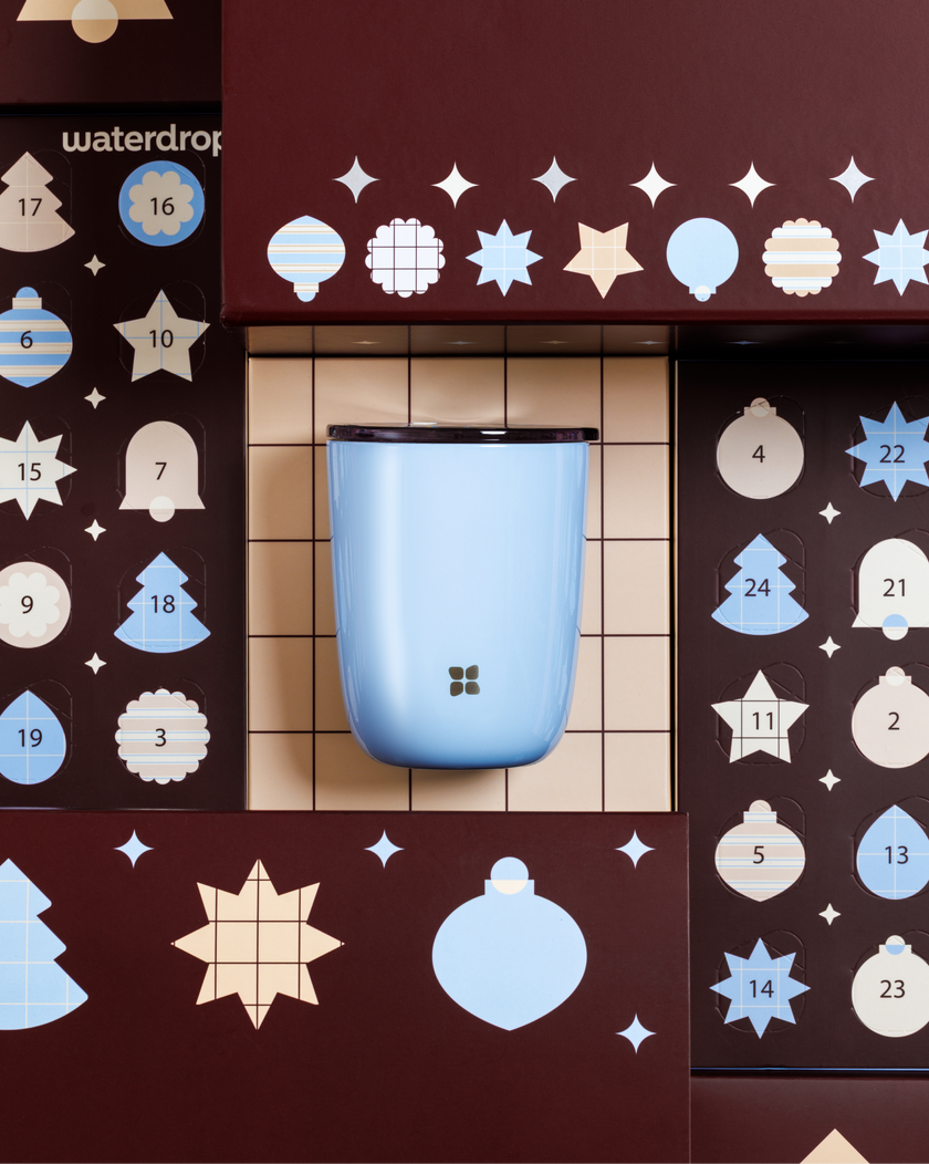 Recipiente azul claro y redondeado montado en un panel de madera con recortes decorativos en forma de círculos y estrellas.