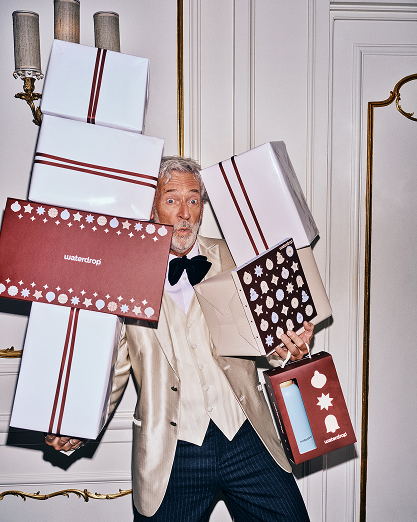Hombre con traje beige lleva varios regalos envueltos en interiores.