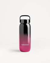 Botella de agua con degradado de negro a rosa, tapa negra y asa.
