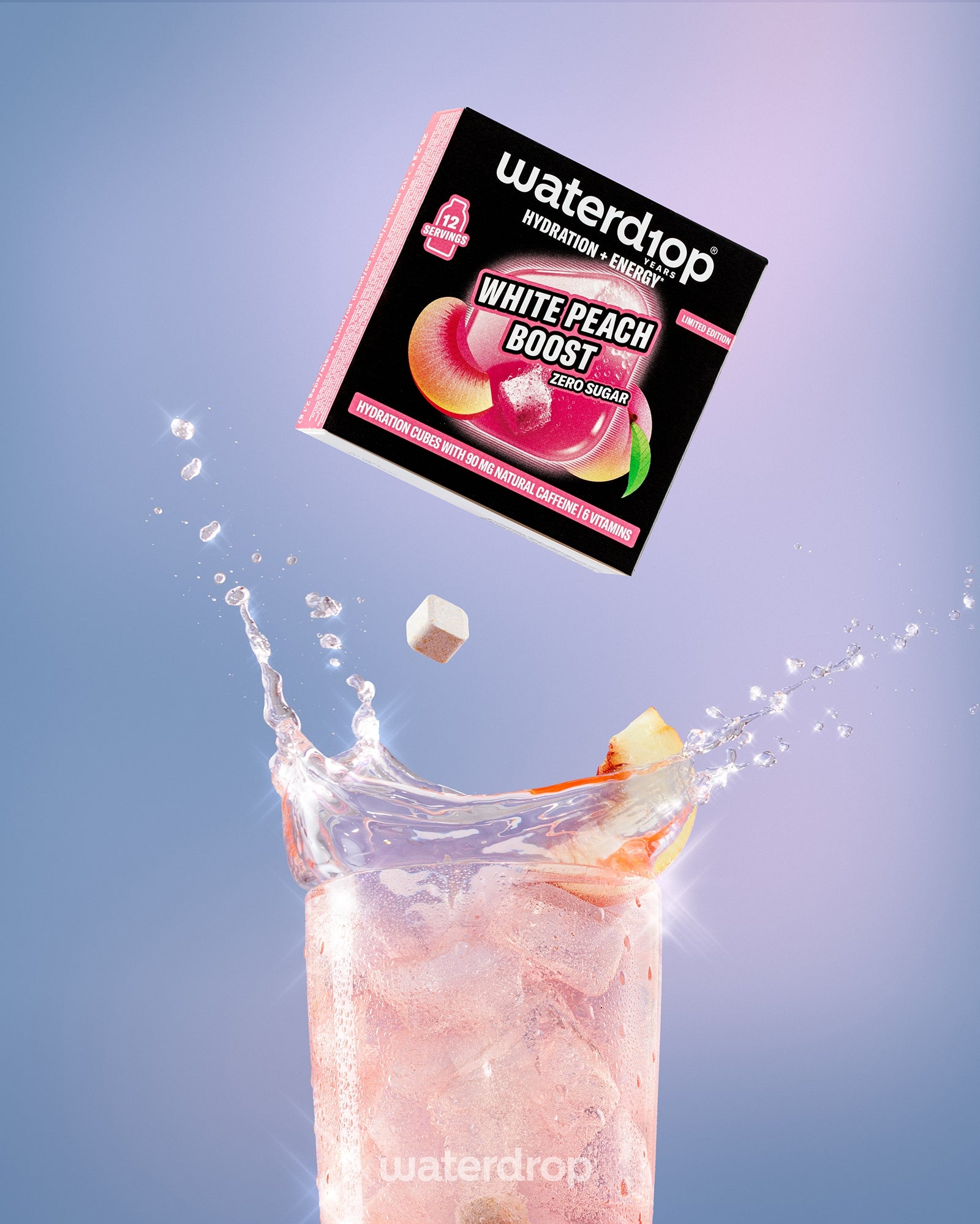 Caja de mezcla White Peach Boost suspendida sobre una bebida rosada con hielo en un vaso alto.