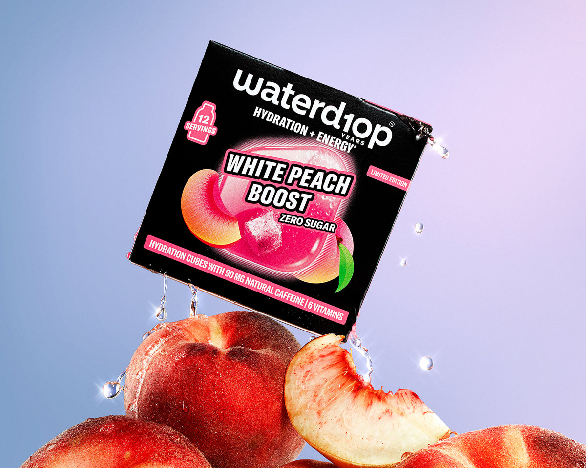 Caja de bebida de hidratación y energía sobre una pila de duraznos con gotas de agua, fondo degradado rosa y azul.