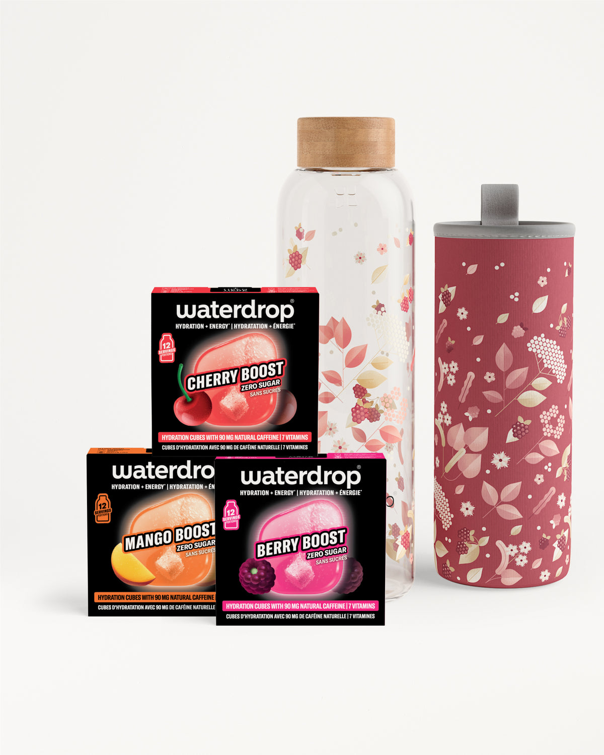 Conjunto de tres sobres de flavor boost junto a una botella de vidrio transparente con tapa de madera y un vaso alto rosa con diseño floral.