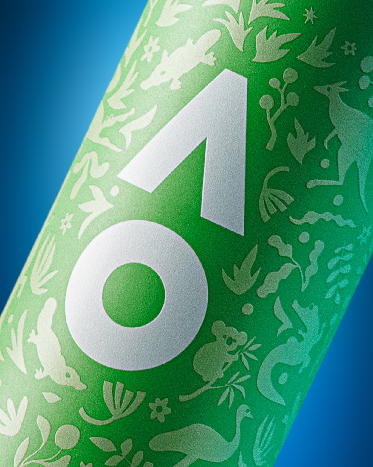 Primer plano de una botella cilíndrica verde con un gran emblema blanco geométrico y siluetas decorativas blancas sobre fondo azul.