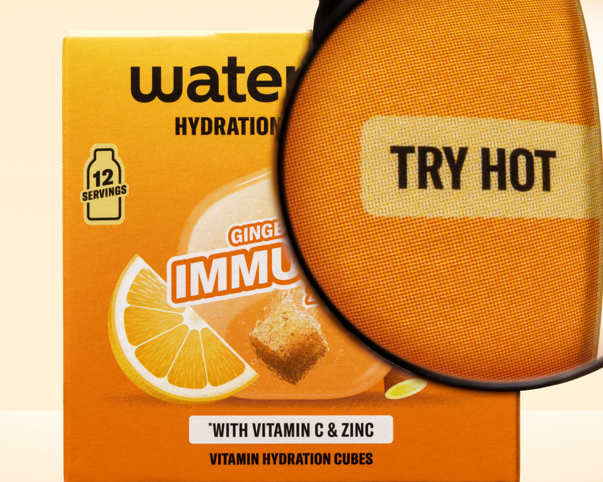 Caja naranja con gráfico de limón y una lupa superpuesta, promoción de cubos de hidratación con vitaminas.
