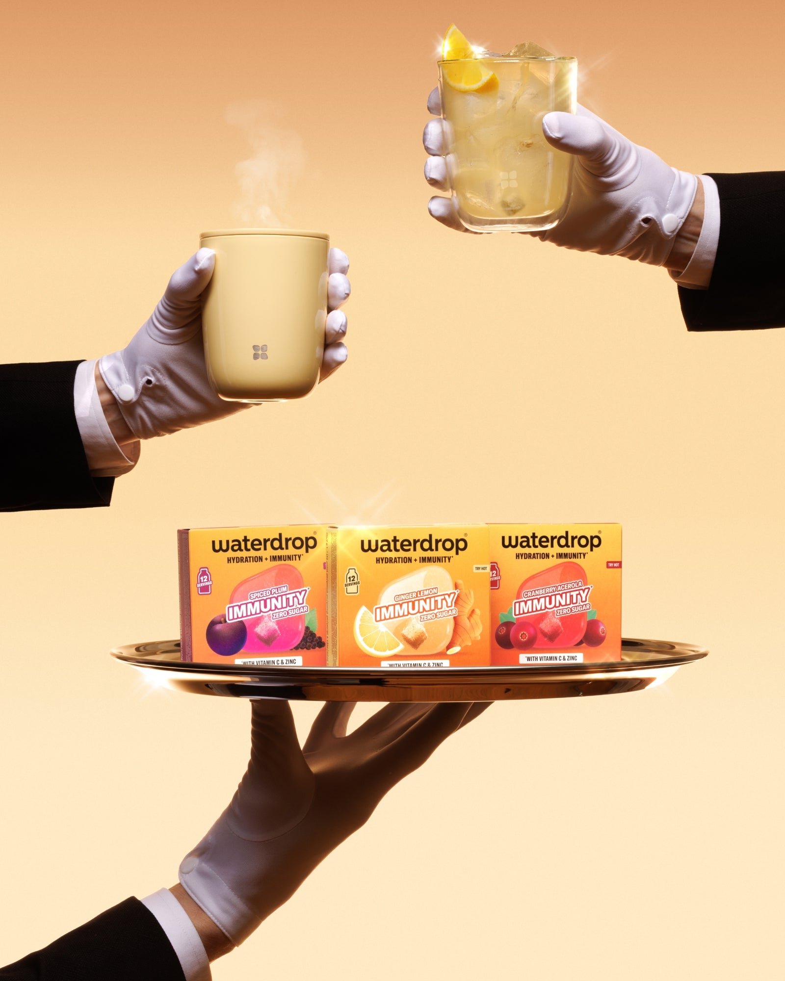 Manos con guantes sostienen una bandeja con tres cajas Waterdrop y dos tazas calientes contra un fondo naranja cálido.